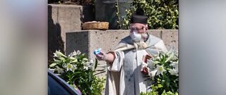 Priest using water gun for holy water