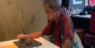 Man solves two Rubik's cubes without looking