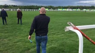 Man jumps horse race hurdle