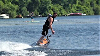 Man skillfully rides a futuristic jet powered surf board