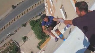 Young man does "bottle flip challenge" hanging from building