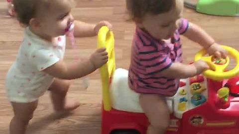 Baby preciously pushes twin sibling in toy car