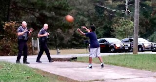 Police Officers Play Basket Ball With Young Boy