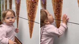 Confused toddler tries licking picture of ice cream cone