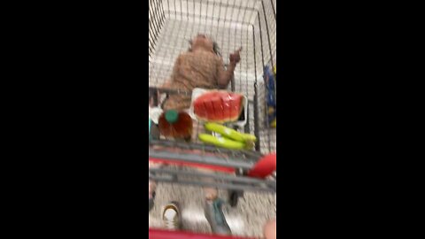 Kid rides under the shopping cart while mom is grocery shopping.mp4