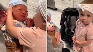 One-year-old girl excitedly meets her newborn baby brother