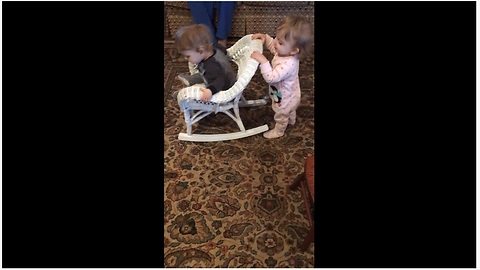 Baby girl pushes twin brother in rocking chair