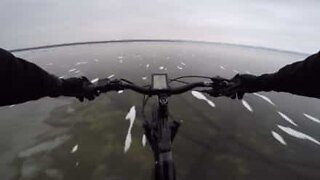 Cyclist crosses transparent frozen lake