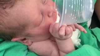Premature baby drinks milk from a cup