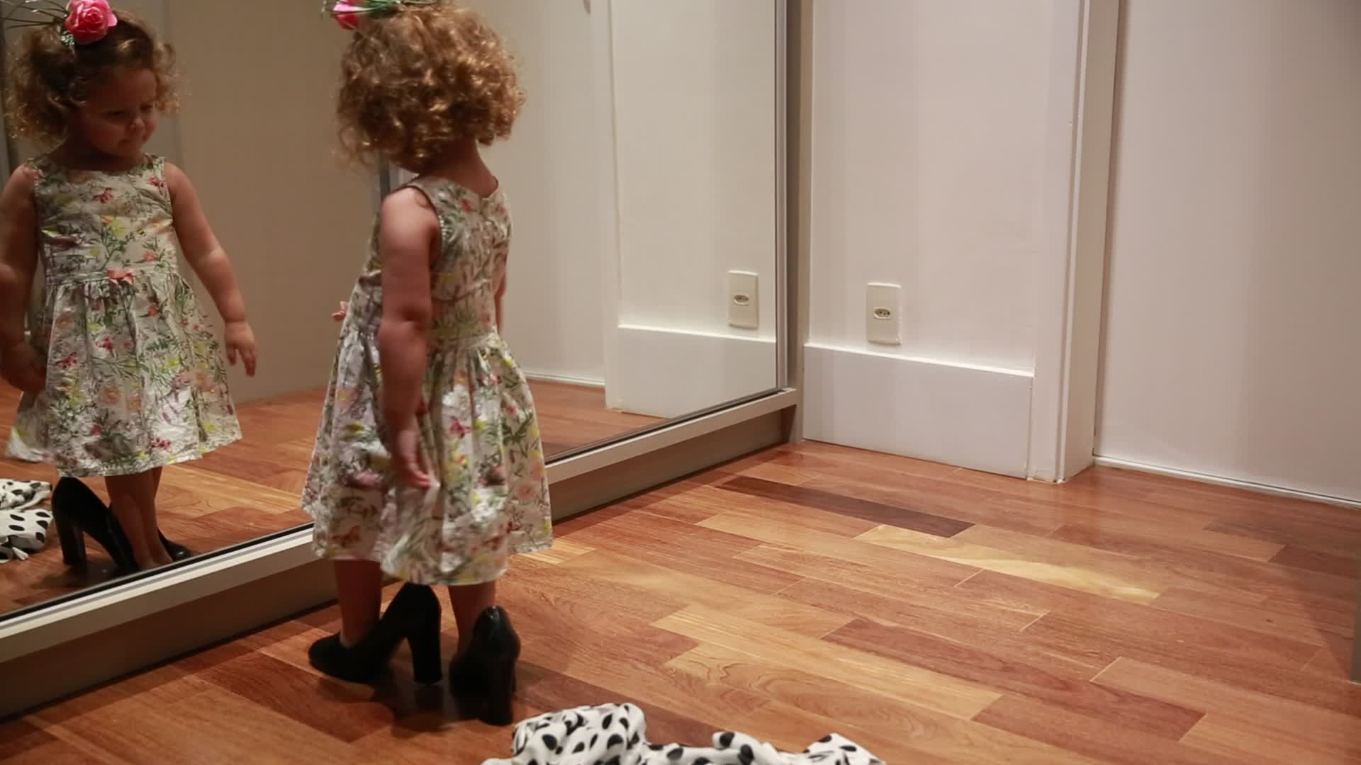 Девочка в маминых туфлях перед зеркалом