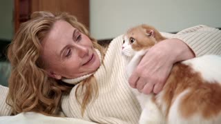 A WOMEN PETTING HER CUTE CAT ON HER BED
