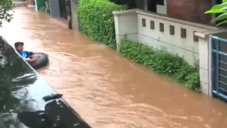 Kid floats down tube in flooded streets of Jakarta