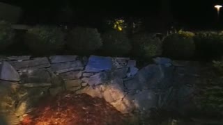 Guy runs off of rocks into blue lit crescent pool dive water