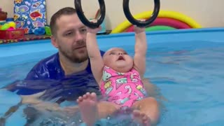 Baby incredibly hangs from rings in the pool