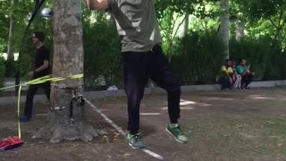 Guy does a backflip while walking a slackline and lands on his crotch