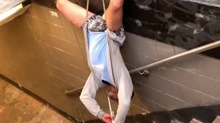 Musician Plays While Hanging Upside Down at Subway Entrance