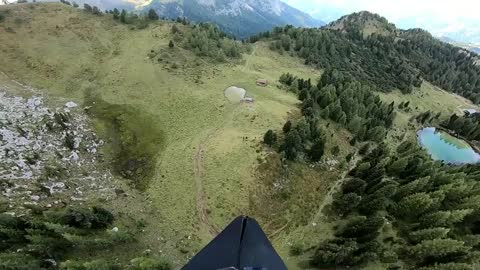 Aerial View Of Person Paragliding Over Hills And Snow-covered Mountain