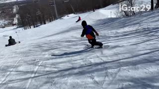 Snowboarder rides off small ramp and falls down on his butt