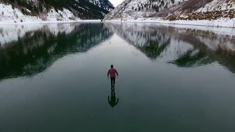 Stunning drone footage of man skating on perfectly frozen lake