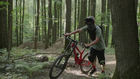 A Mountain Biker Walking with his Bike in a Forest