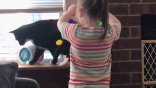 Little girl decorates cat with Christmas lights