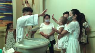Baby high-fives priest during her own baptism