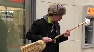 Street performer turns broom into electric guitar