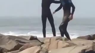 Surfer doing stretches on a rocky shore