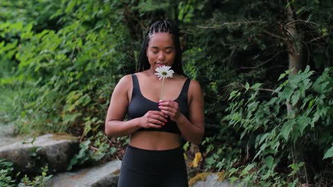 A Woman in Activewear Smelling a Flower
