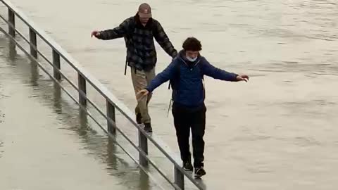 Daredevils walk along banister over flooded river in Paris