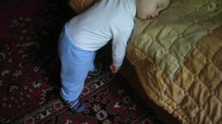 The child is SLEEPING STANDING with a toy in his hands!