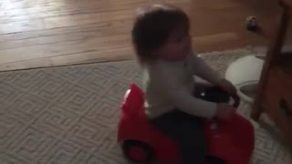 Small kid on red toy motorcycle falls back