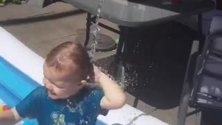 Toddler loves getting water poured on him