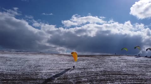 Group Of People Paraglide Over Snow-covered Mountains