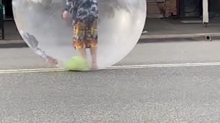 Performer Sings in Bubble While Rolling Down the Road