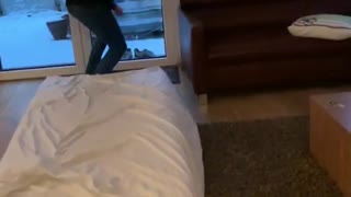 Guy in sunglasses slides down stairs with bed shoots gun and tumbles forward