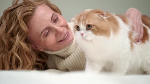 A Woman Petting Her Cat On Bed