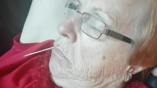 Grandma sleeps on couch with toothpick dangling out of her mouth