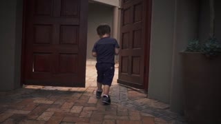 A young child runs from the door to play