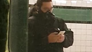 Man outside subway wearing black gas mask